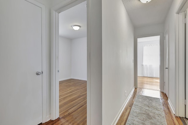 hallway with light wood-type flooring and baseboards