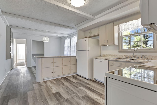 kitchen featuring a textured ceiling, a peninsula, white appliances, light wood-style floors, and beamed ceiling