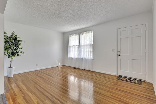 interior space featuring a textured ceiling, light wood-type flooring, and baseboards