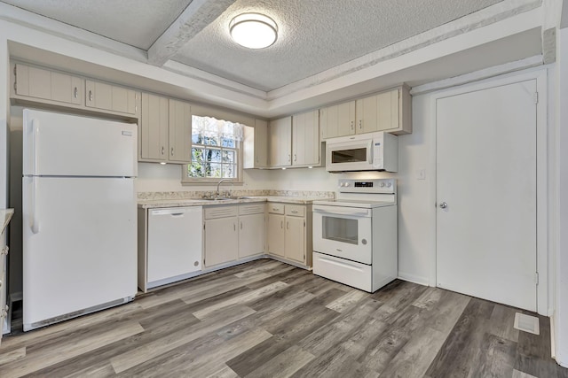 kitchen with light countertops, cream cabinets, light wood-style floors, a textured ceiling, and white appliances