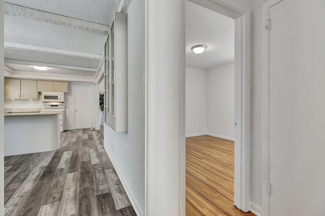 hallway featuring a textured ceiling, baseboards, and wood finished floors