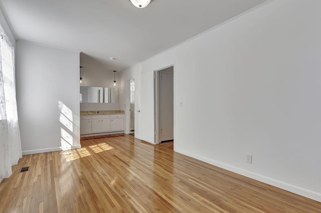 unfurnished living room featuring light wood-style floors, visible vents, and baseboards