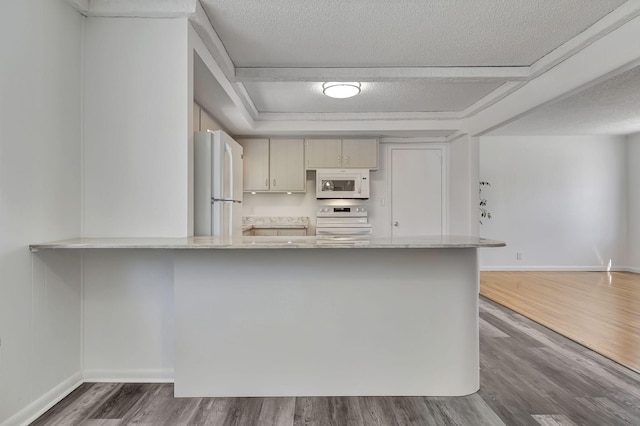 kitchen with a peninsula, white appliances, a textured ceiling, and wood finished floors