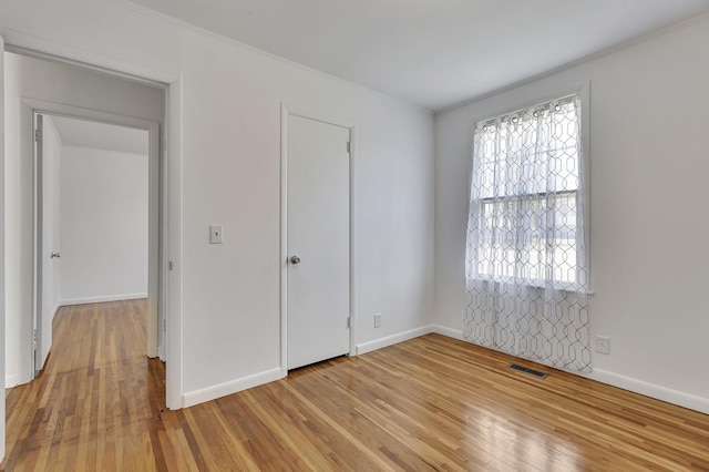 unfurnished bedroom with light wood-type flooring, visible vents, and baseboards