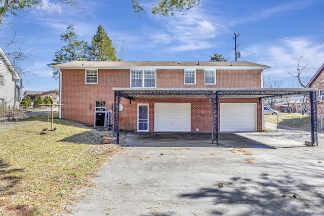 exterior space featuring an attached garage, a yard, aphalt driveway, and brick siding