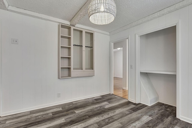 unfurnished bedroom with a textured ceiling, dark wood-type flooring, and baseboards