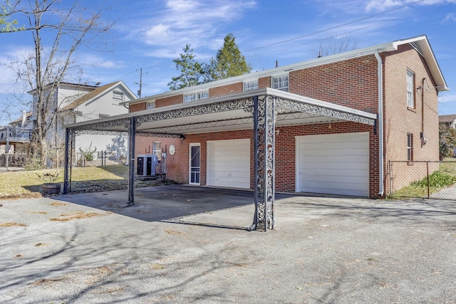 view of front of property featuring brick siding, an attached garage, central AC unit, fence, and driveway