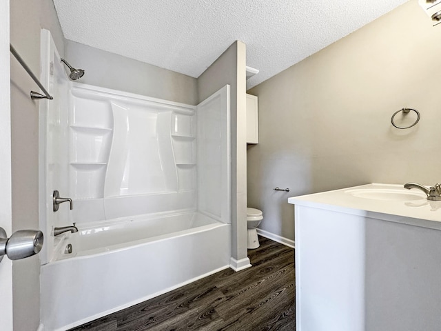 full bath featuring baseboards, toilet, wood finished floors, tub / shower combination, and a textured ceiling