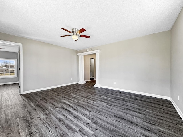 empty room with a textured ceiling, baseboards, dark wood finished floors, and a ceiling fan