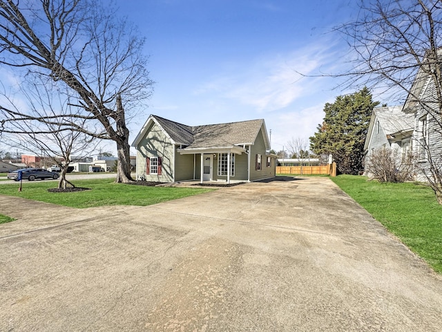 view of front of house with driveway, a front lawn, roof with shingles, and fence