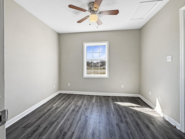 empty room featuring a textured ceiling, ceiling fan, dark wood-type flooring, baseboards, and attic access