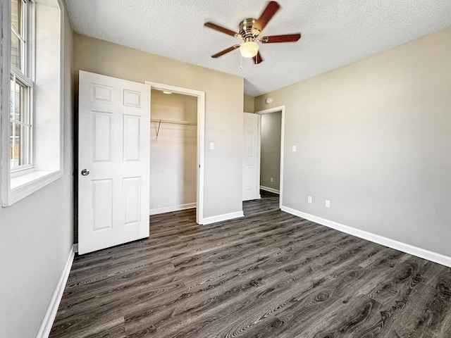 unfurnished bedroom featuring dark wood-type flooring, a textured ceiling, and baseboards