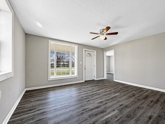 foyer with dark wood finished floors, a textured ceiling, and baseboards