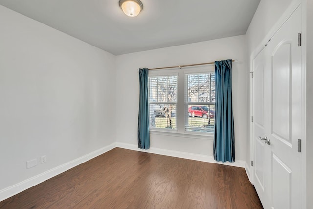 spare room featuring dark wood-style floors and baseboards