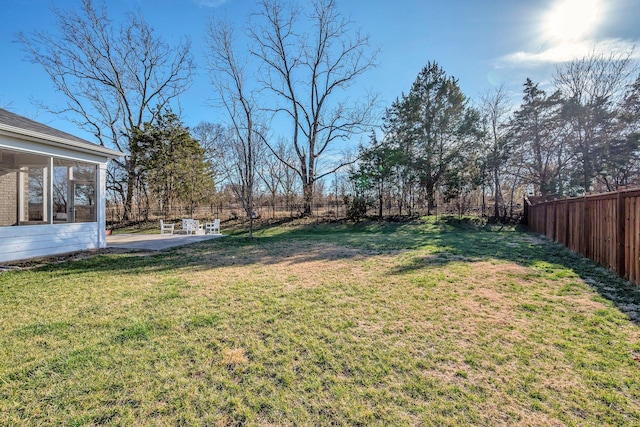 view of yard featuring a sunroom, a fenced backyard, and a patio area