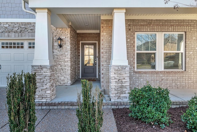 property entrance featuring a garage, stone siding, and covered porch