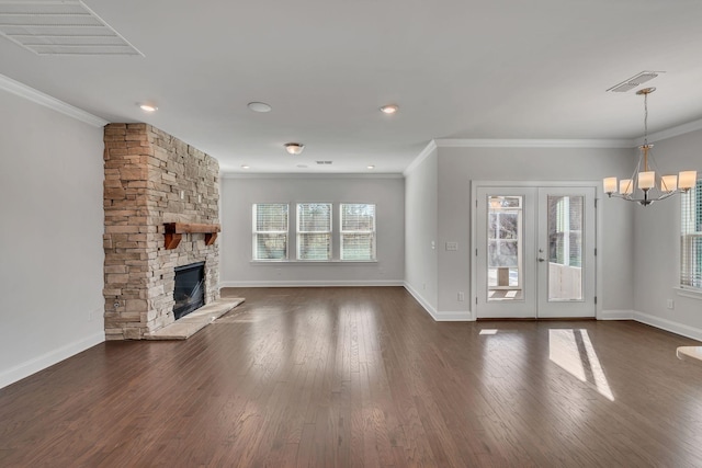 unfurnished living room featuring visible vents, dark wood finished floors, a wealth of natural light, and a stone fireplace