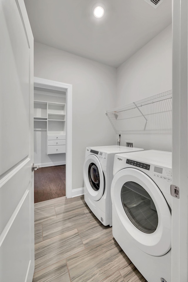 washroom featuring laundry area, light wood finished floors, visible vents, baseboards, and washing machine and dryer