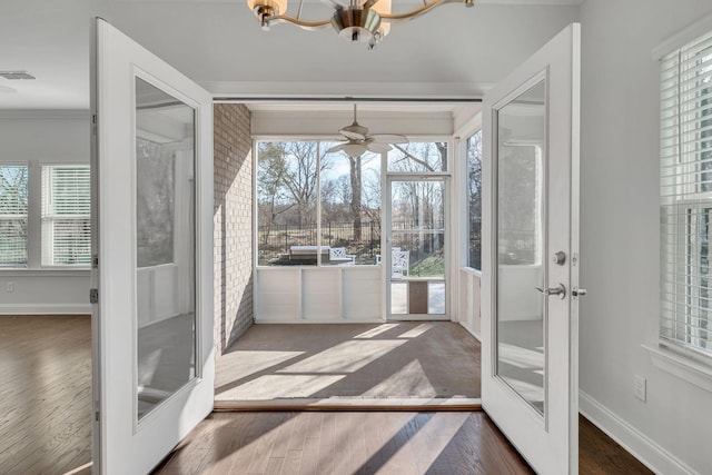 sunroom with ceiling fan with notable chandelier, visible vents, and french doors