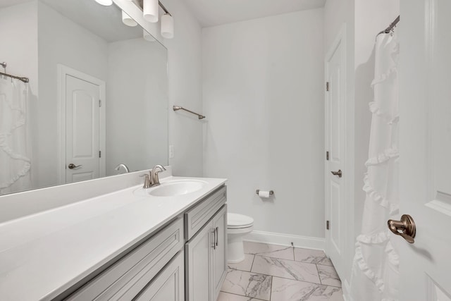 bathroom with toilet, marble finish floor, vanity, and baseboards