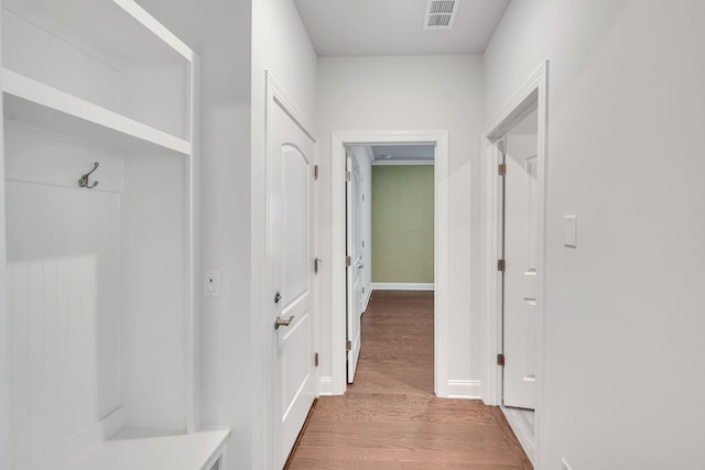 corridor featuring visible vents, baseboards, and wood finished floors