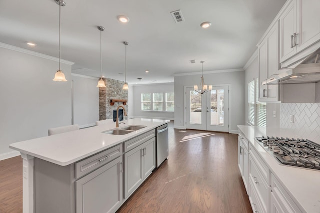 kitchen with dark wood finished floors, stainless steel appliances, tasteful backsplash, ornamental molding, and a sink