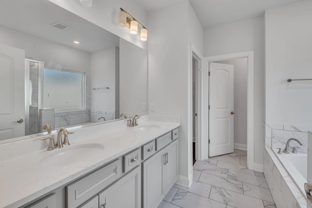 full bathroom featuring marble finish floor, double vanity, a sink, and a bath