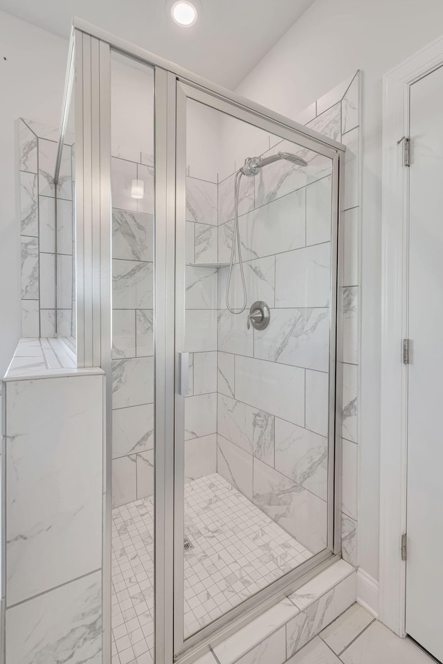 bathroom featuring marble finish floor and a shower stall