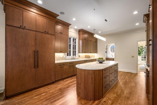 kitchen featuring a kitchen island, light countertops, a sink, and wood finished floors