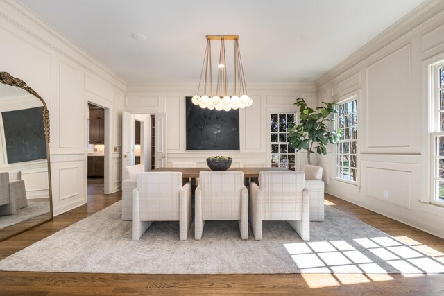 dining area with ornamental molding, an inviting chandelier, and a decorative wall