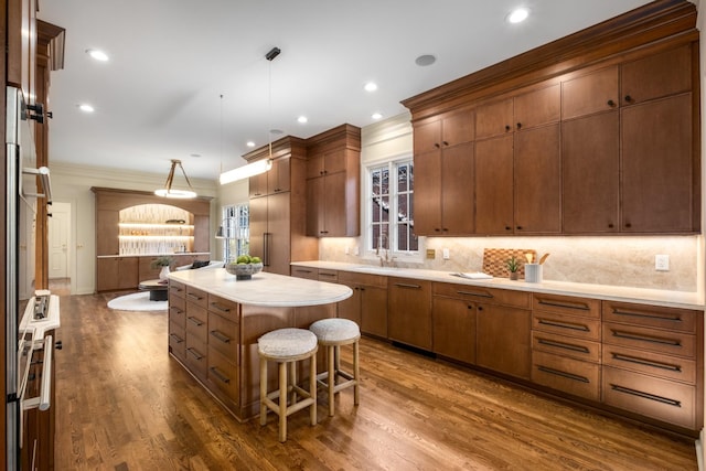 kitchen with a center island, tasteful backsplash, ornamental molding, dark wood-type flooring, and a sink