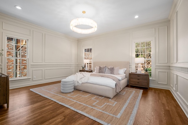 bedroom with dark wood-style floors, a decorative wall, and crown molding