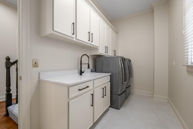 washroom featuring cabinet space, baseboards, ornamental molding, independent washer and dryer, and a sink