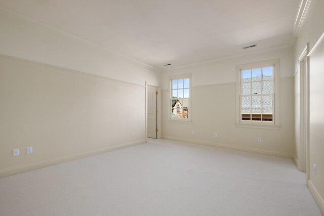 spare room featuring baseboards, crown molding, visible vents, and light colored carpet