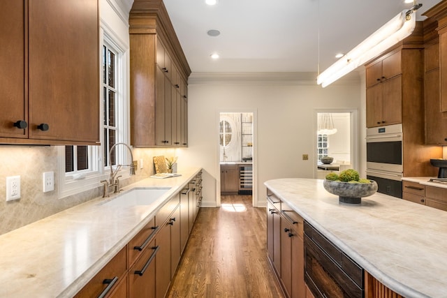 kitchen with beverage cooler, a sink, light countertops, decorative backsplash, and crown molding