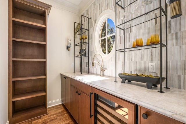 bar featuring beverage cooler, decorative backsplash, wood finished floors, crown molding, and a sink