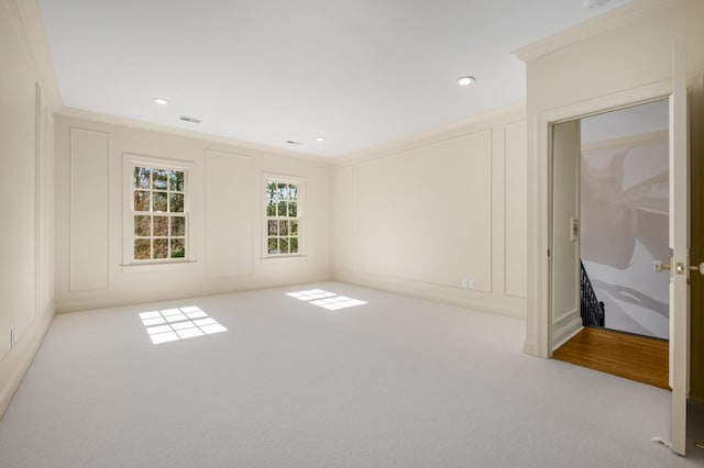 empty room with ornamental molding, carpet, visible vents, and a decorative wall