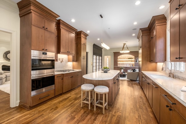 kitchen with appliances with stainless steel finishes, a center island, a sink, and dark wood-style floors