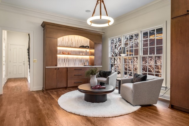 living area with crown molding, baseboards, and wood finished floors