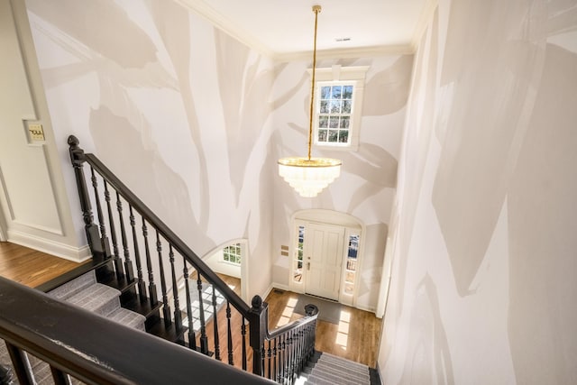 entrance foyer with stairway, an inviting chandelier, ornamental molding, wood finished floors, and baseboards