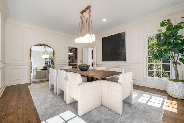 dining room with a notable chandelier, crown molding, a decorative wall, and wood finished floors