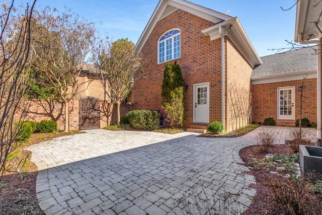 view of front of home with entry steps, brick siding, and a gate