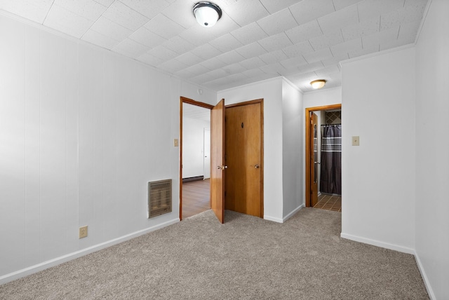 interior space featuring baseboards, carpet, visible vents, and crown molding