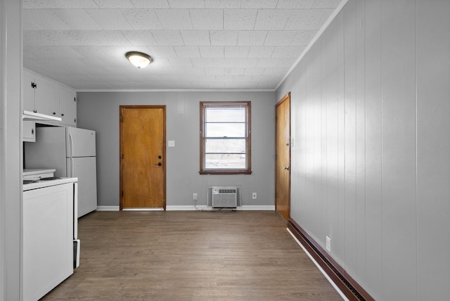 kitchen with stove, wood finished floors, white cabinets, a wall mounted air conditioner, and crown molding