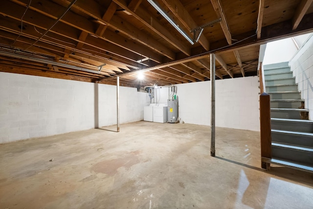 unfinished below grade area with water heater, stairway, and separate washer and dryer