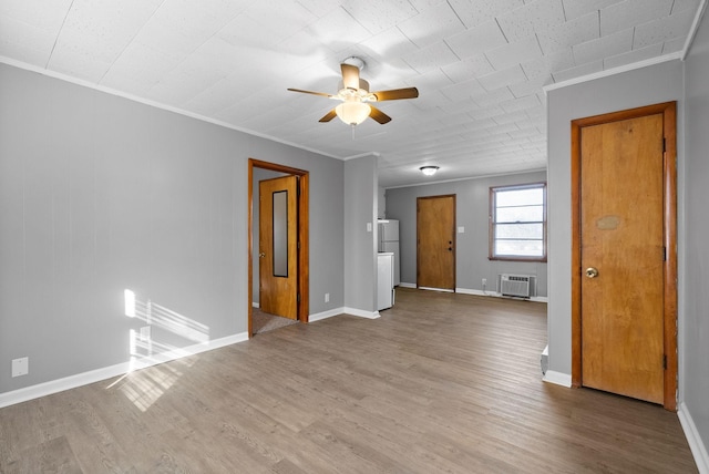 unfurnished room featuring ornamental molding, a ceiling fan, wood finished floors, a wall mounted air conditioner, and baseboards