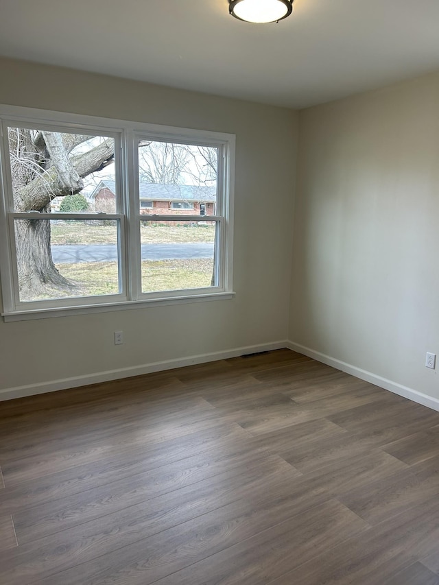 empty room featuring dark wood-style floors and baseboards