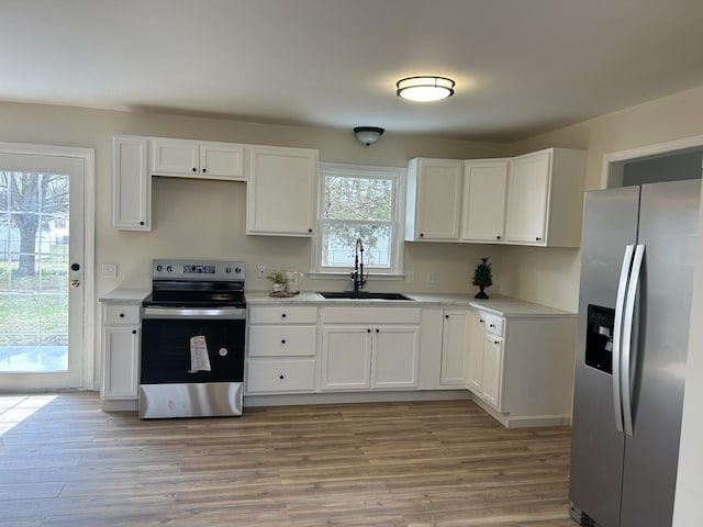 kitchen featuring a sink, white cabinetry, light countertops, appliances with stainless steel finishes, and light wood-type flooring