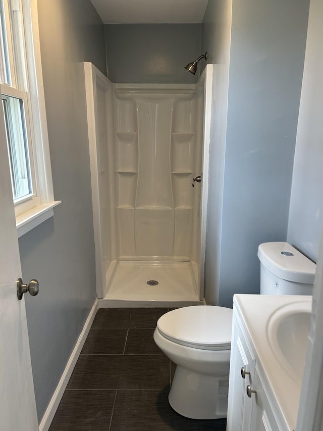 full bathroom featuring baseboards, vanity, toilet, and walk in shower