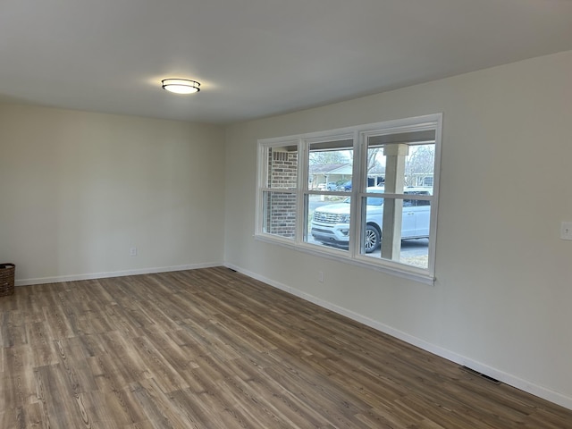 unfurnished room with wood finished floors, visible vents, and baseboards